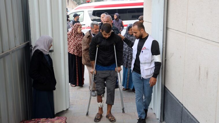 Profissional de MSF auxilia paciente com lesão na perna em uma clínica de cuidados pós-operatórios montada dentro do Hospital de Campanha Indonésio de Rafah, no sul de Gaza. Dezembro de 2023 (Foto: MSF)